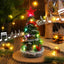 Light-up Christmas tree music box ornament with glowing lights on a shelf
