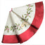 White holly embroidered Christmas tree skirt in white on a wooden floor with presents underneath a decorated tree