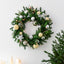 Green pine leaf garland with warm lamp lights hanging on a door at Christmas