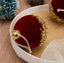 Burgundy flocked glass Christmas ornament hanging on tree branch with warm lighting