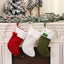 Knitted striped Christmas sock ornament hanging on tree with red and green accents