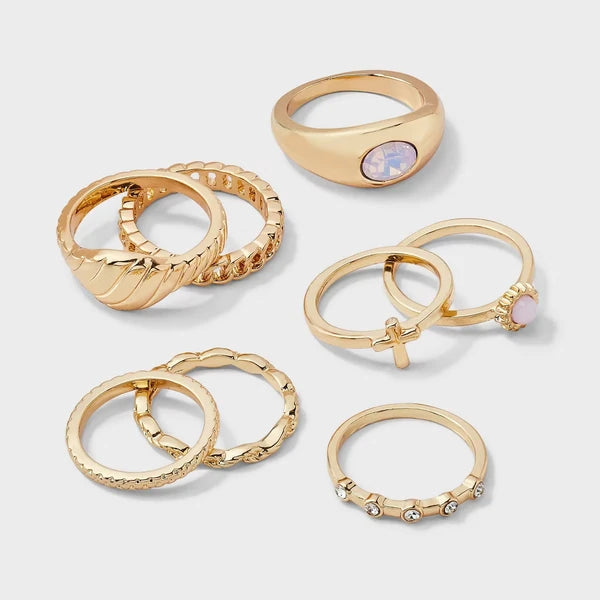 Stacked gold-tone faith rings showing cross and sun designs worn together
