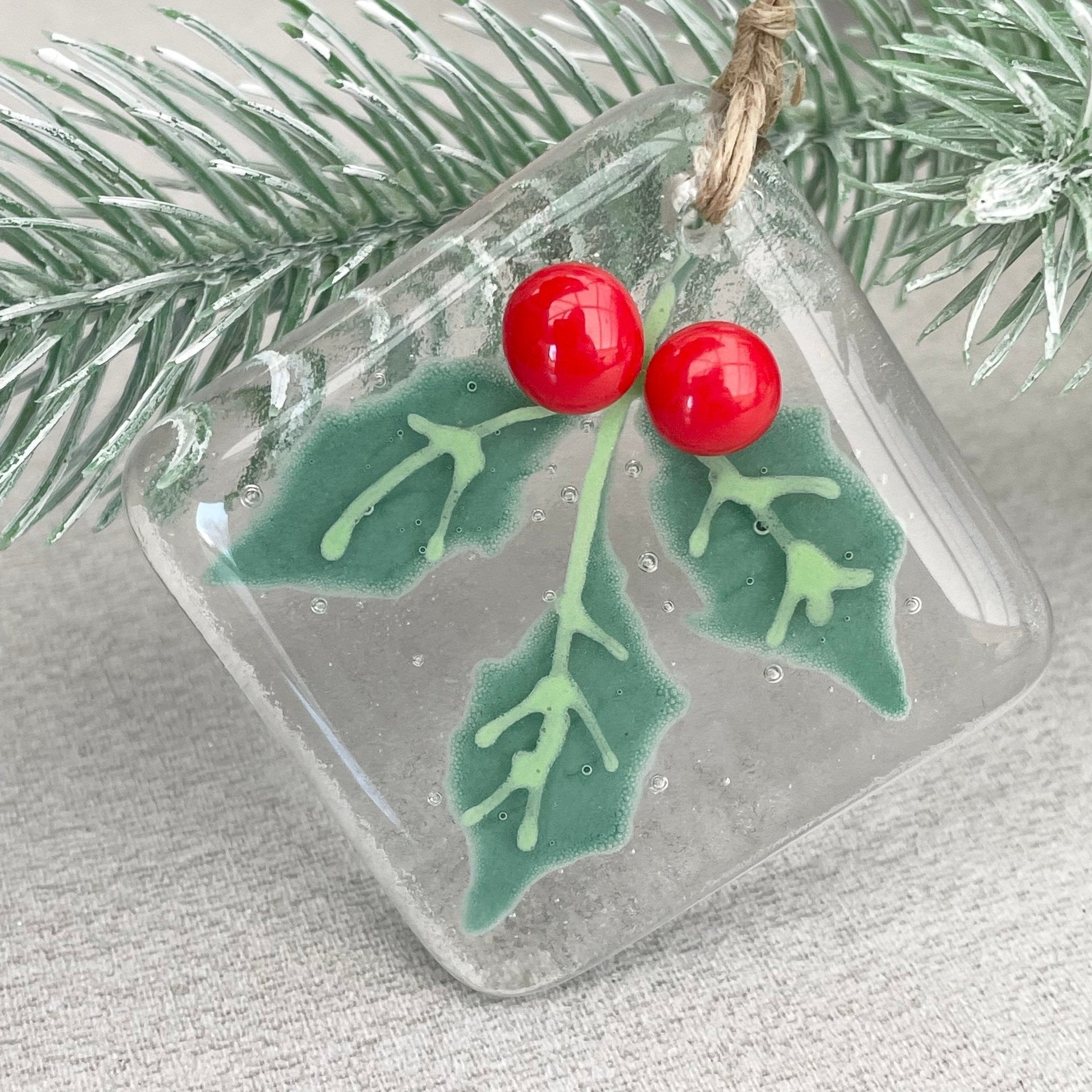 Glass Christmas tree pendant with faceted design suspended on branch Main image