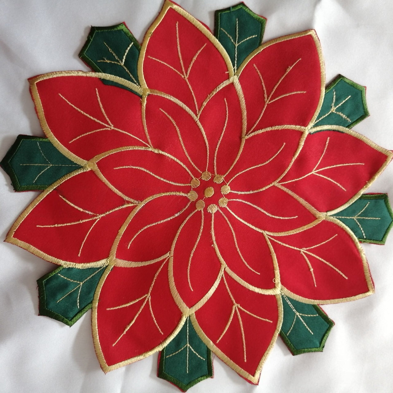 Red and filled embroidered tablecloth displayed on garden table outdoors
