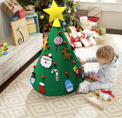 Child assembling felt cone tree with bright decorative balls on flat surface