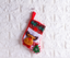 Christmas sock ornament displayed on decorated tree with lights and garland