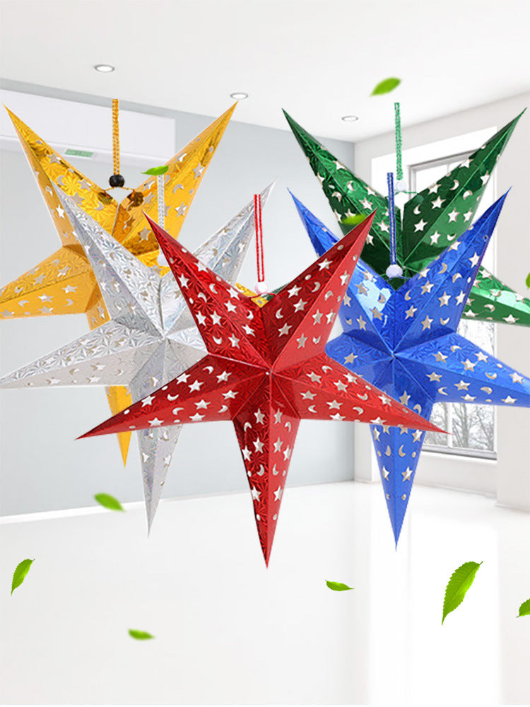 Gold five-pointed star Christmas ornament hanging on decorated tree