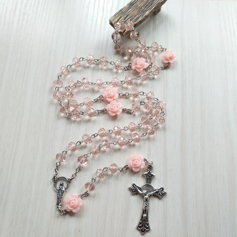Detailed look at geometric cross pendant on pink necklace chain