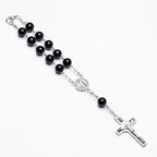 Rosary bracelet with dripping cross connector on neutral background