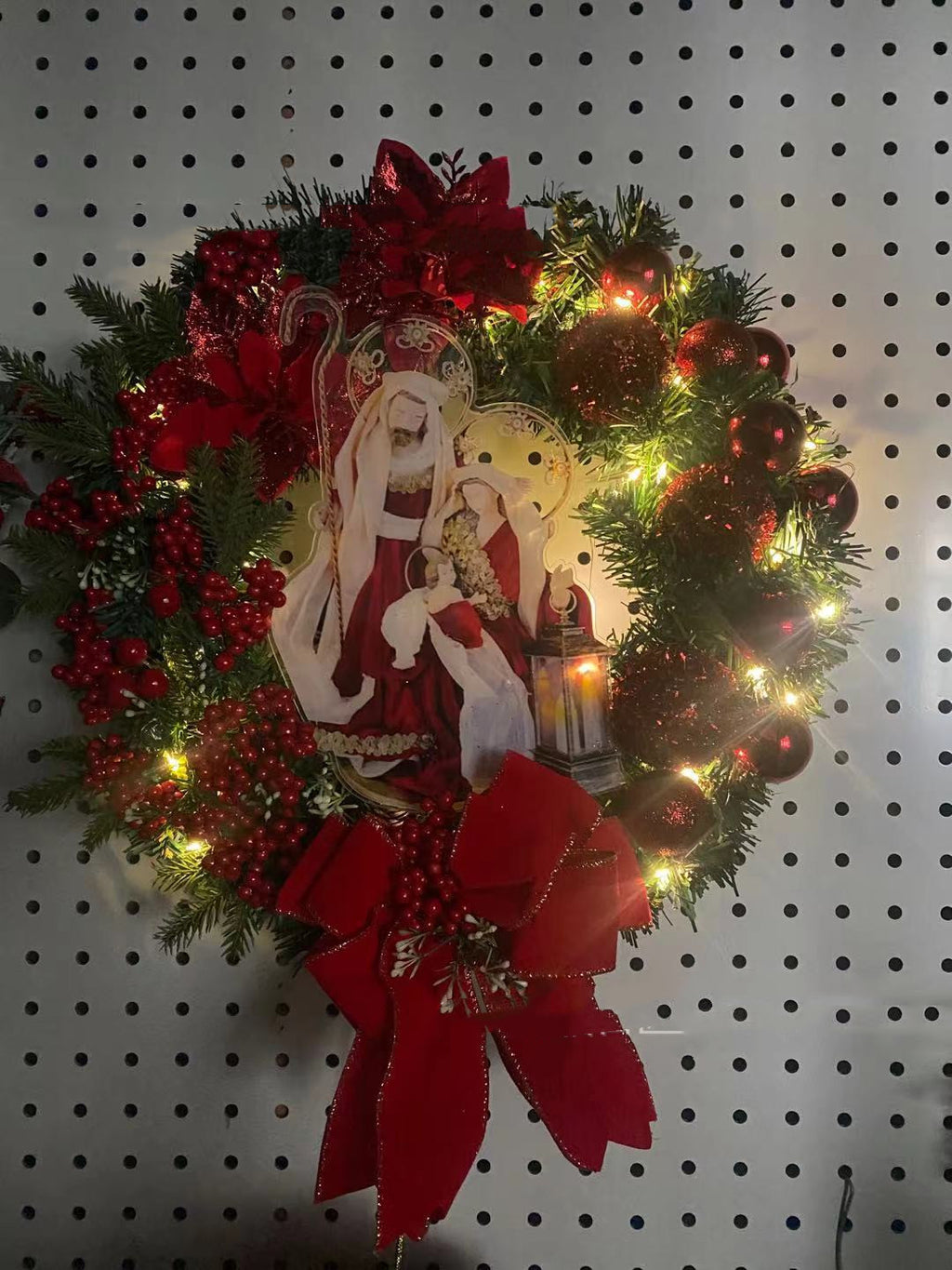 Festive illuminated garland wreath with religious Jesus design glowing warmly outdoors