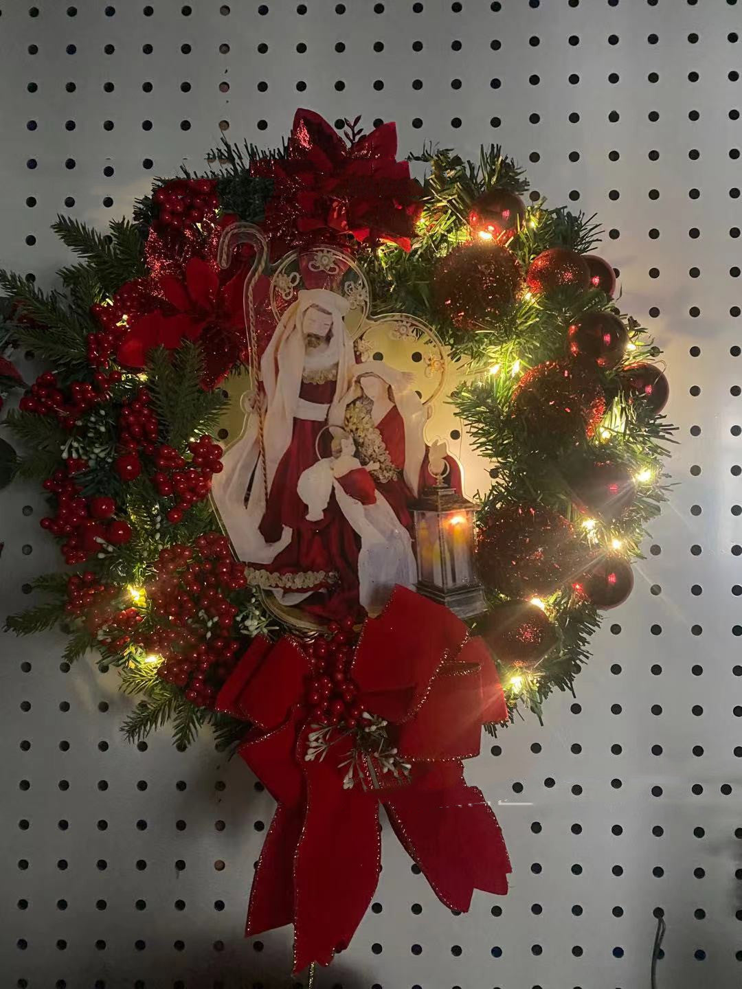 Festive illuminated garland wreath with religious Jesus design glowing warmly outdoors