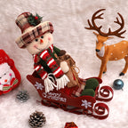 Grouped Christmas ornaments including sled dolls on snowy surface