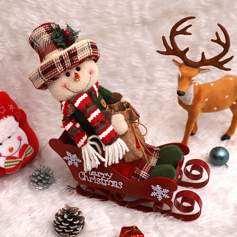 Grouped Christmas ornaments including sled dolls on snowy surface