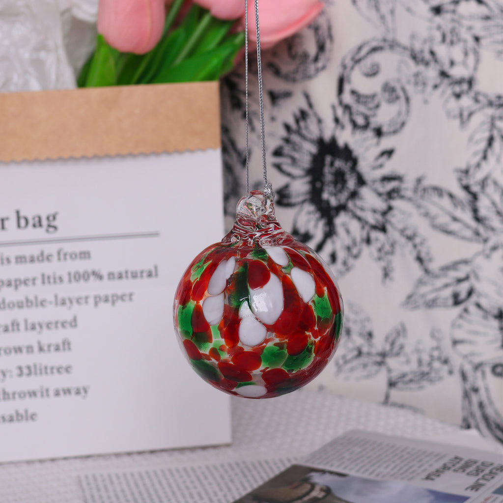 Transparent glass bauble ornament catching light against a Christmas tree