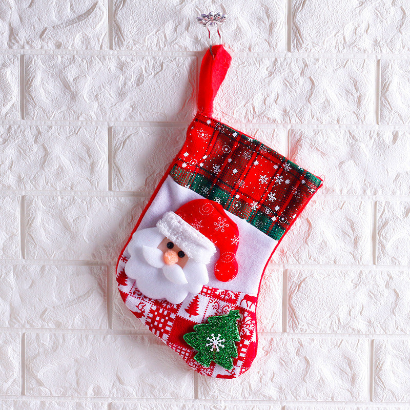 Christmas sock ornament hanging from tree branch with red ribbon