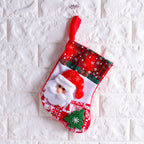 Christmas sock ornament hanging from tree branch with red ribbon