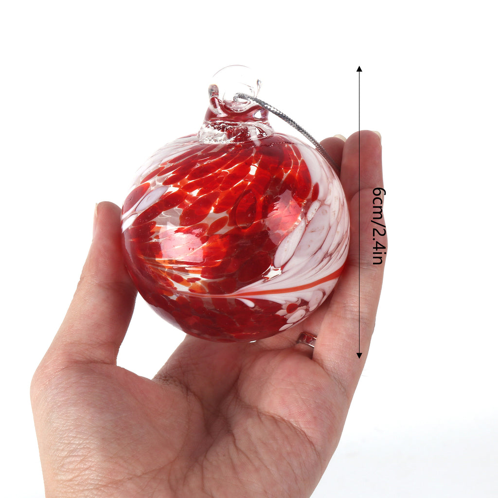 Hand-blown glass ball ornament displayed with evergreen branches and ribbon