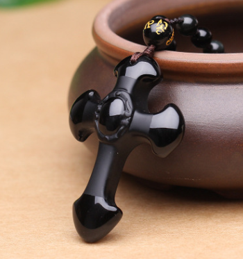 Close-up of polished obsidian cross pendant - faith accessory