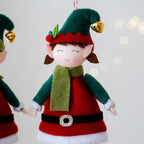 Boy elf doll pendant on green Christmas tree branch, festive decor
