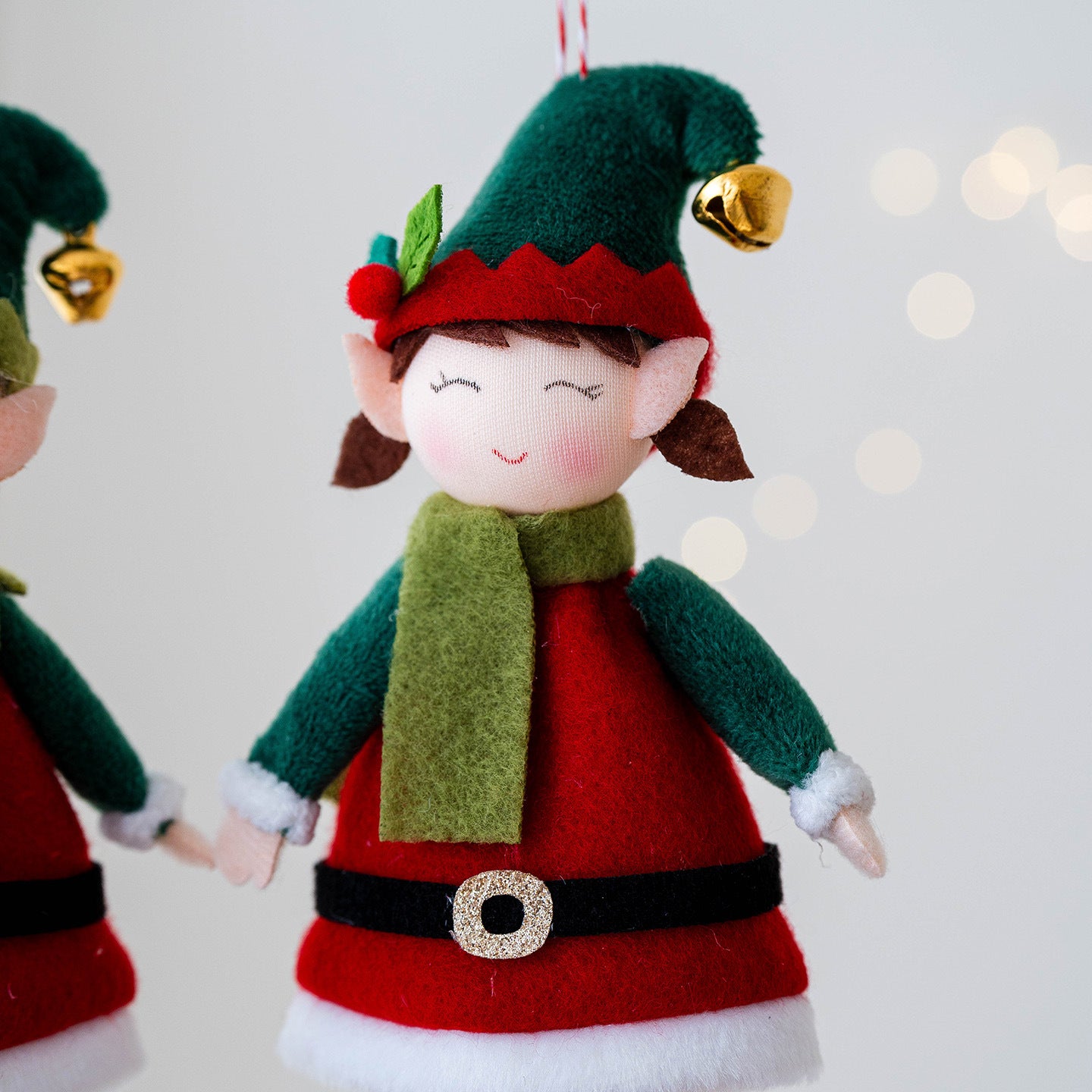 Boy elf doll pendant on green Christmas tree branch, festive decor
