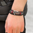 Jesus Cross Leather Bracelet displayed on rustic wooden surface