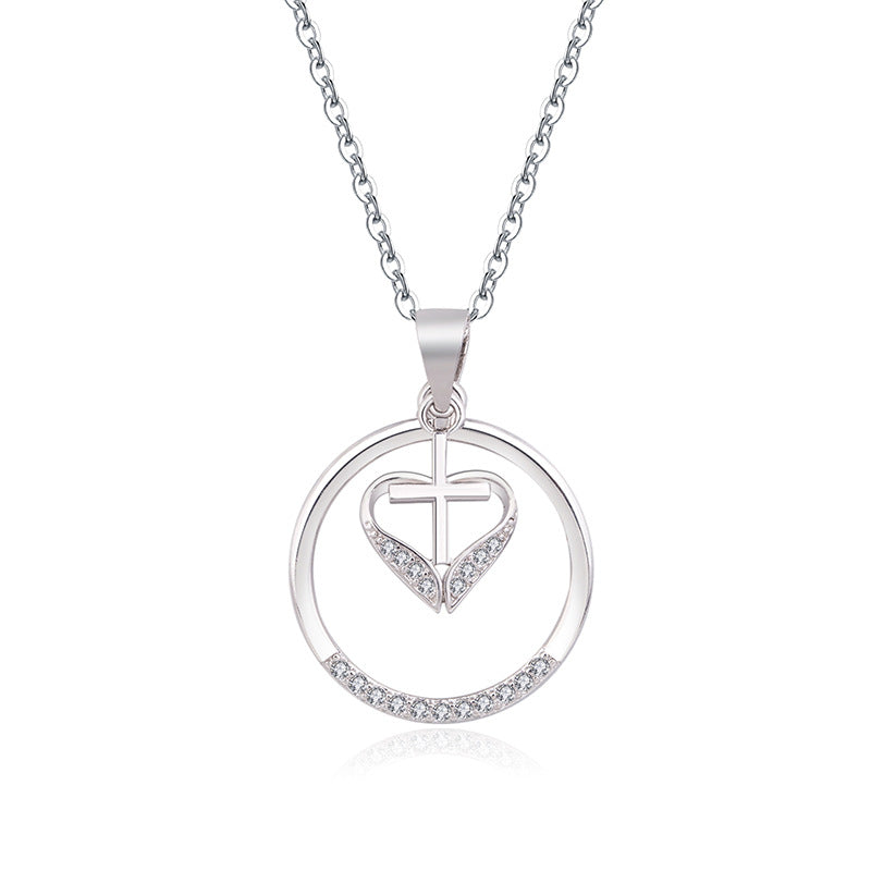 Silver heart cross pendant displayed on chain against soft background