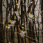 Transparent angel ornament hanging gracefully on a Christmas tree with warm lights
