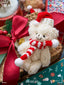 Festive plush Christmas ornament displayed on a decorated tree surrounded by holiday greenery