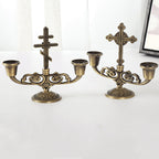 Single cross style candle holder ornament beside a lit candle for ambiance