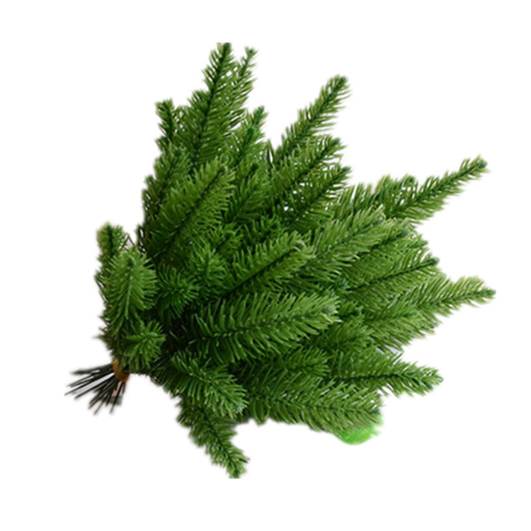 Pine needle sprays displayed with Christmas ornaments and festive decorations in warm lighting