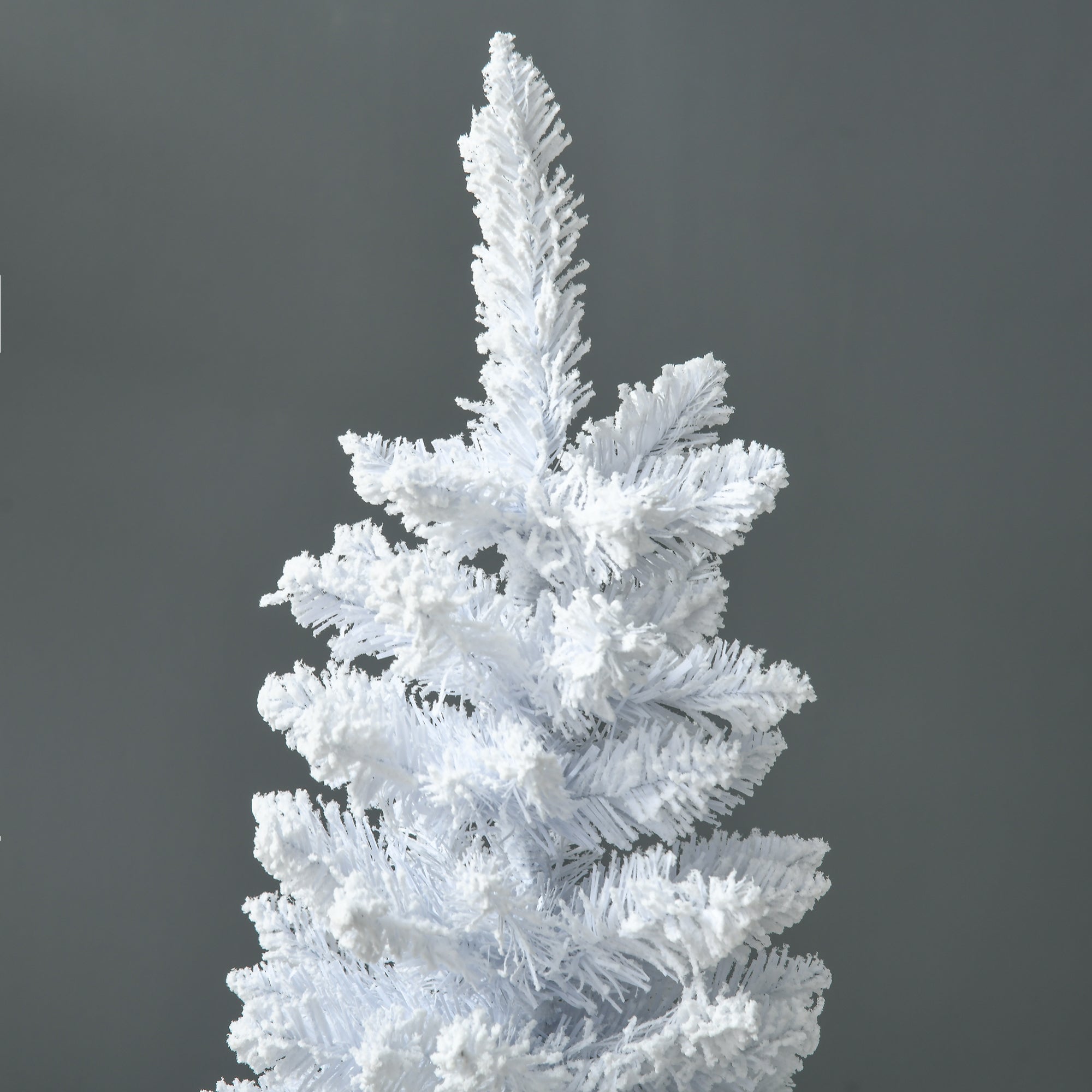 White pencil Christmas tree standing next to a fireplace with holiday decorations
