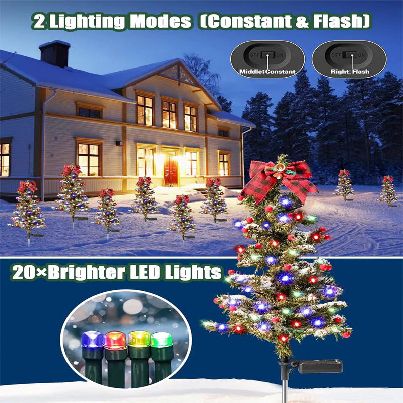 Solar Christmas tree stake light glowing warmly in a nighttime winter garden setting with soft white lights