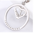 Close-up view of heart pendant showcasing detailed cross engraving on silver surface