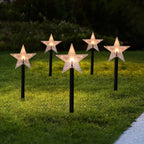 Snowflake-shaped solar garden light glowing softly in winter garden setting