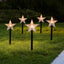Snowflake-shaped solar garden light glowing softly in winter garden setting