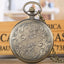 Round pocket watch face showing Virgin Mary and Jesus religious motif in silver-tone metal
