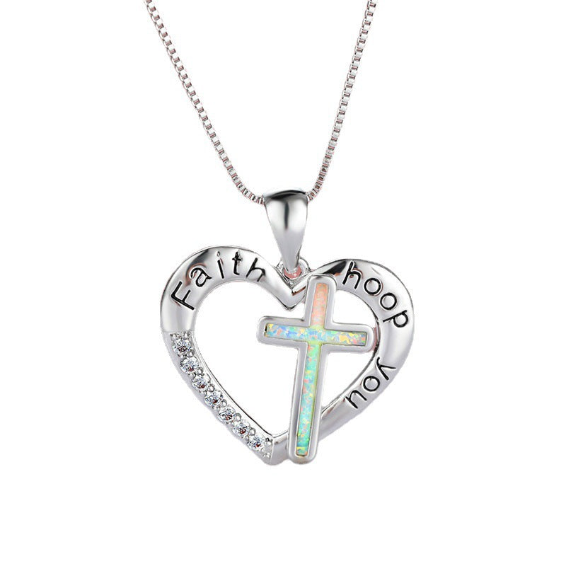 Close-up of the gold-plated pendant featuring a cross and heart symbol with imitation opal inlay
