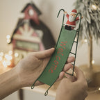 Green old man Christmas ornament sliding on window ledge in wrought iron