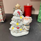 Luminous ceramic Christmas ornament showing a cozy winter cottage scene