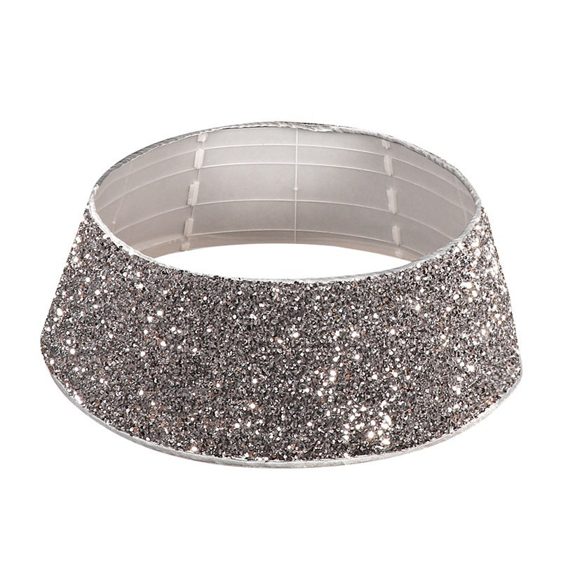 Decorated Christmas tree base with silver gray sequin tree skirt framing the stand