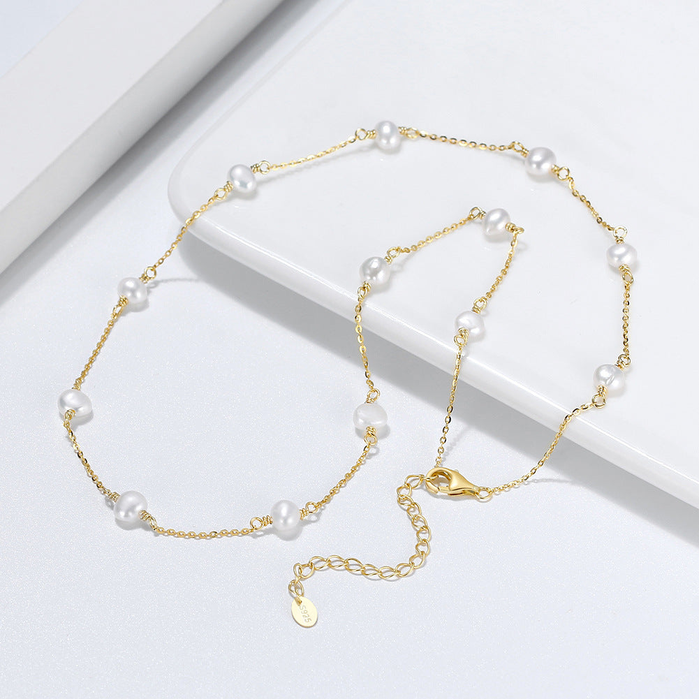 Close-up of pearl accent on silver cross chain necklace