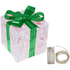 Glowing Christmas gift box ornament with warm LED lights on decorative surface