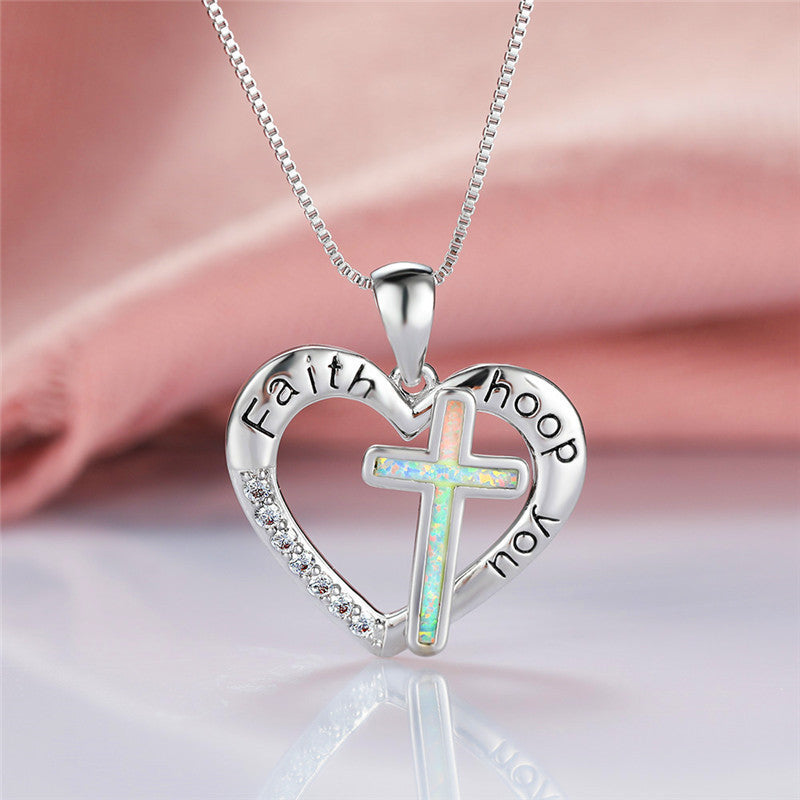Heart-shaped cross pendant with imitation opal displayed on white background