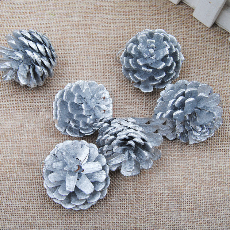 Silver pine cone pendant hanging against dark background showing reflective coated finish