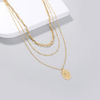 Close-up view of geometric cross pendant on layered necklace chain