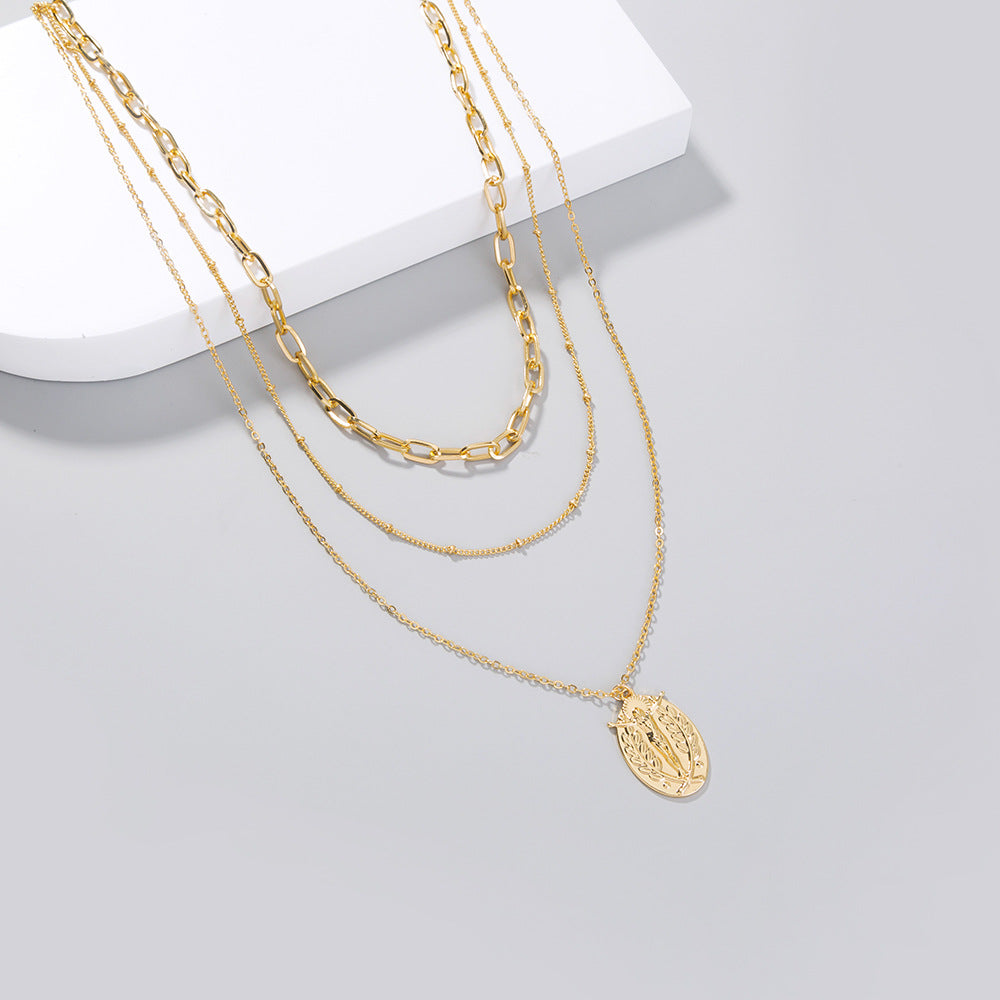 Close-up view of geometric cross pendant on layered necklace chain