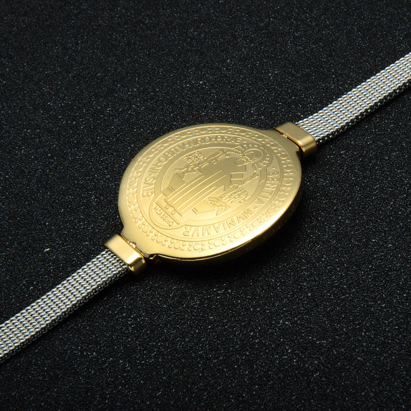 Saint Benedict devotional bracelet laid flat against dark fabric background