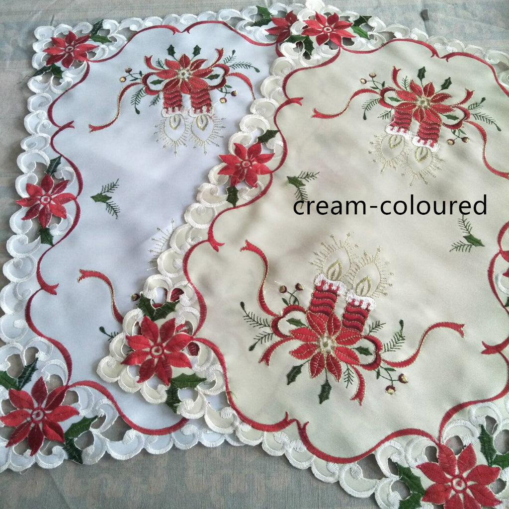 Christmas table setting featuring embroidered tablecloth with decorative centerpiece