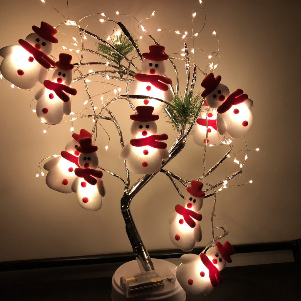 Close-up of cute plush snowman decorations on Christmas string lights
