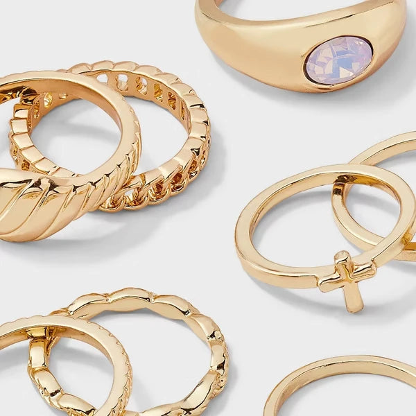 Gold-tone cross and sun ring set with rhinestone details displayed on a warm surface